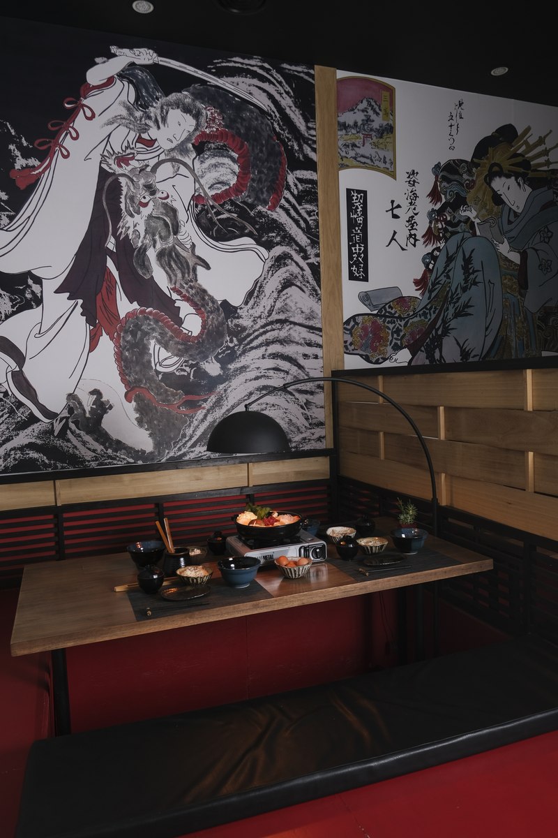 Sala tatami en Harakiri de Una — murales ukiyo-e, cojines rojos y mesa baja tradicional