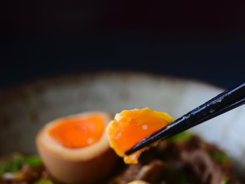 Chopsticks picking marinated egg from gyudon at Harakiri de Una